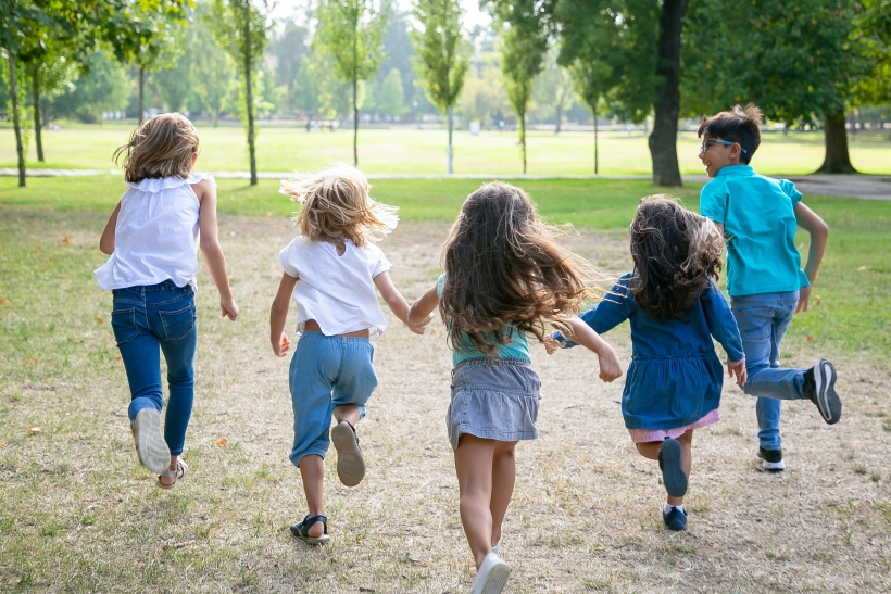 Group kids running grass together having race park back view full length children outdoor activity concept